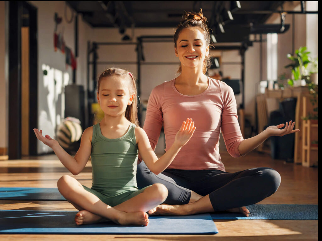 mother and little daughter doing yoga in the gym