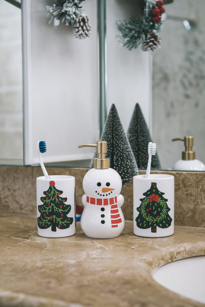 marble bathroom countertop decorated with festive holiday set of ceramic toothbrush holders and soap dispenser