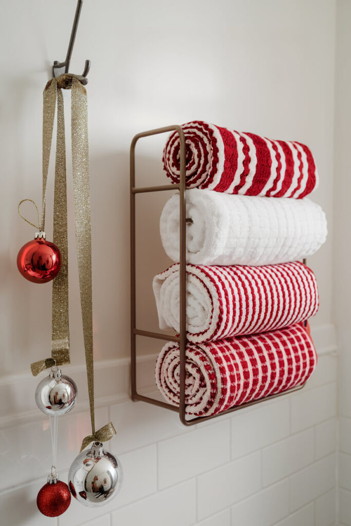 bathroom features a metallic towel rack with rolled towels that look like candy canes and some ornaments