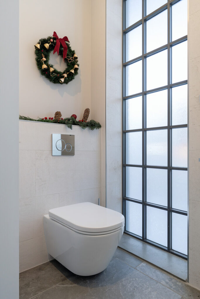 contemporary bathroom with a Christmas wreath above the toilet