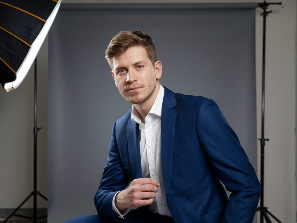 man in a blue suit posing for a portrait in the photo studio