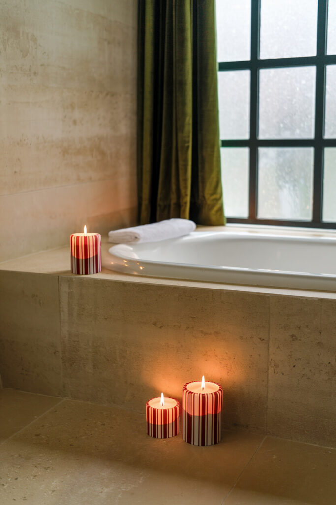 a serene bathroom setting featuring a bathtub and Christmas-themed candles with red and white stripes