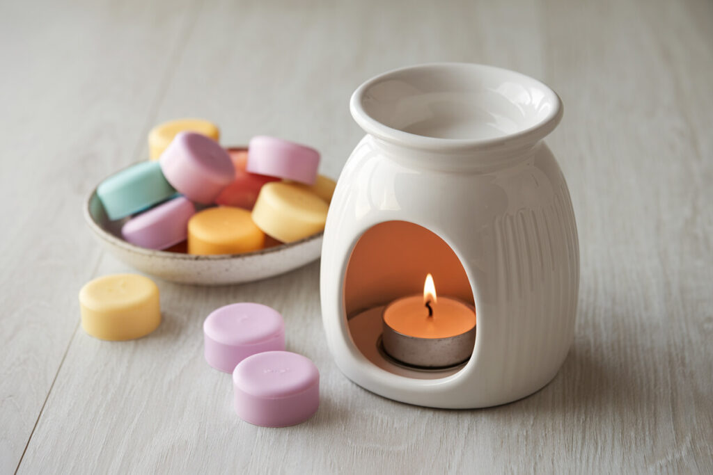 white ceramic wax melt warmer with a few colorful wax melts of pink and yellow colors