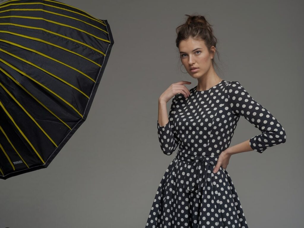 a beautiful woman in a black polka dot dress in the photography studio with a gray backdrop