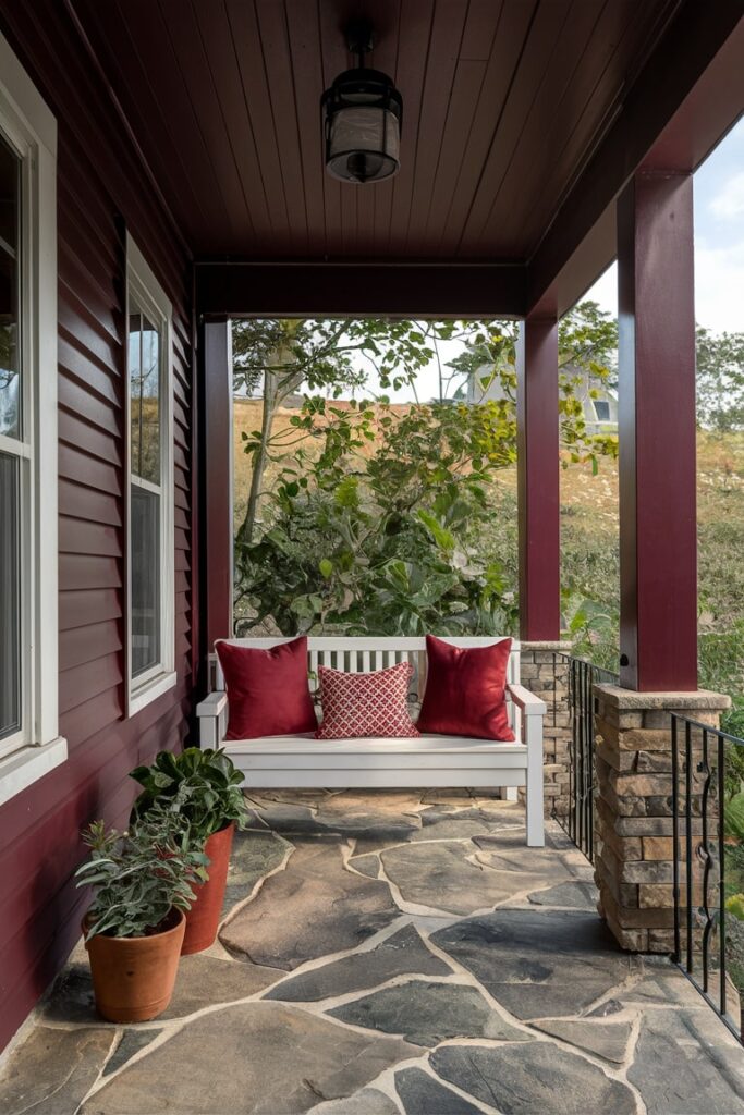 modern back porch with maroon sidings and red pillows on the white bench