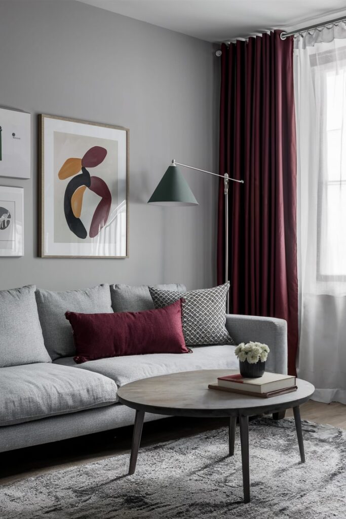 modern light gray living room with gray and maroon decor, maroon curtains and accent pillow, gray couch and walls