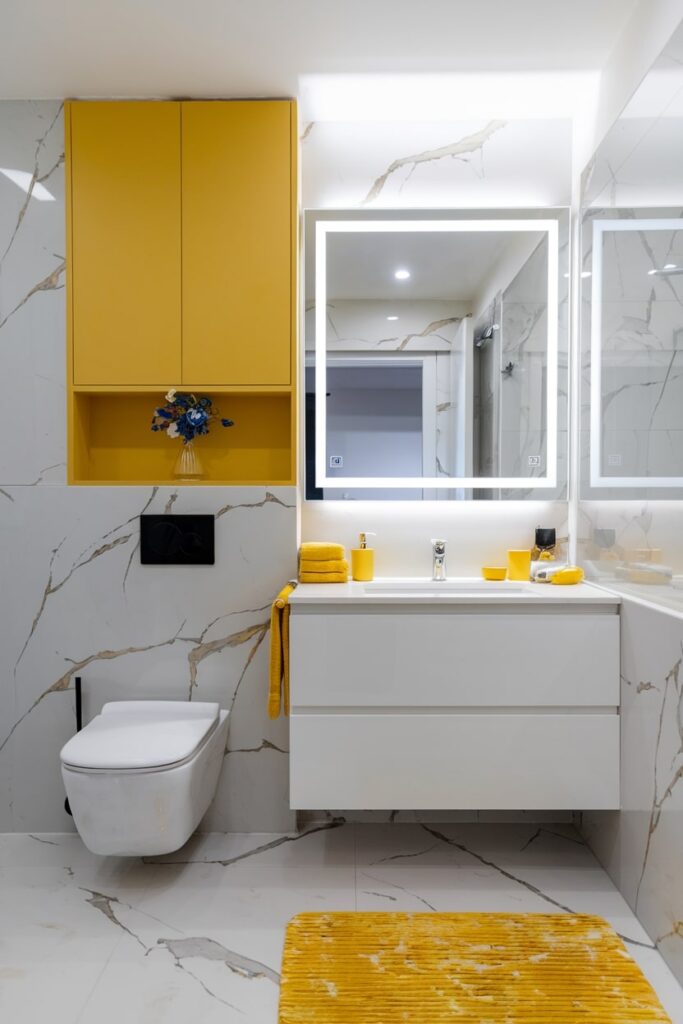 modern white marble bathroom with yellow decor and cabinets