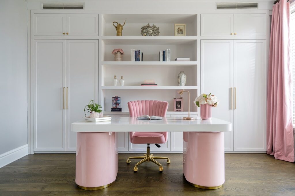 pink and white home office with white built-ins, pink curtains and chair