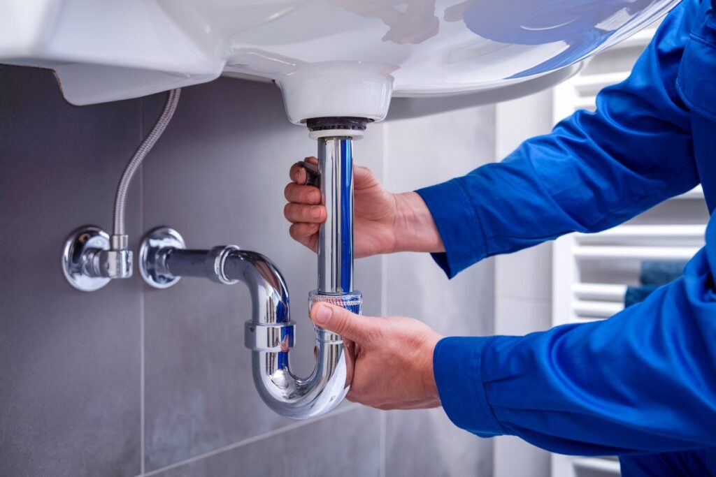 a blue uniformed plumber works on a bathroom plumbing