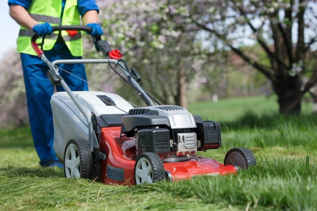 lawn care worker with a red lawn mower