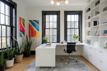 modern and well lit home office with white shelving, black windows