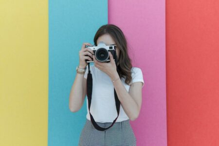 female photographer holding a camera, colorful background