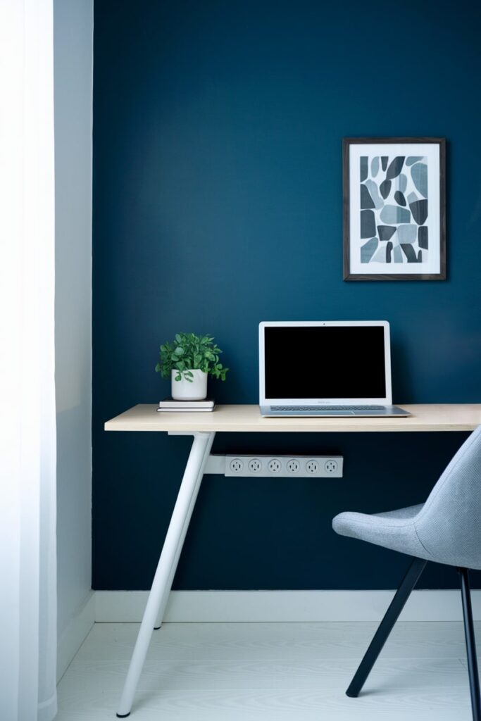 minimalist home office with power strip and dark blue wall