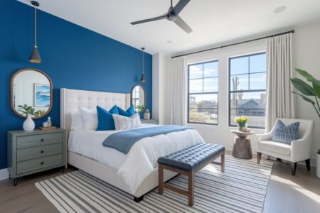 modern bedroom with blue accent wall and black accents, white bed and accent chair