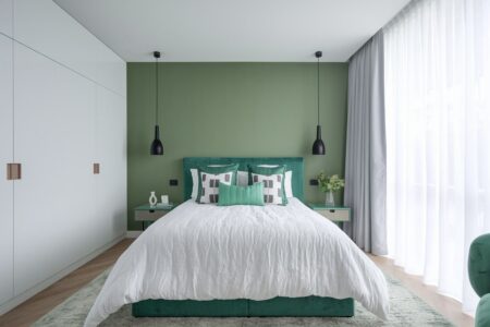 modern bedroom with green accent wall and bed, white bedding