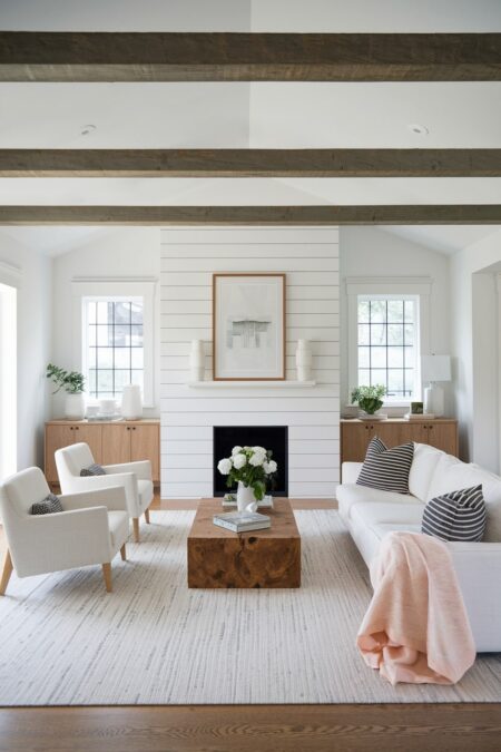 contemporary white living room with exposed wooden beams, hardwood floors, wooden storage cabinets and coffee table