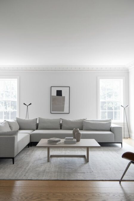 minimalist living room with white walls, light gray sectional sofa and area rug, abstract artwork