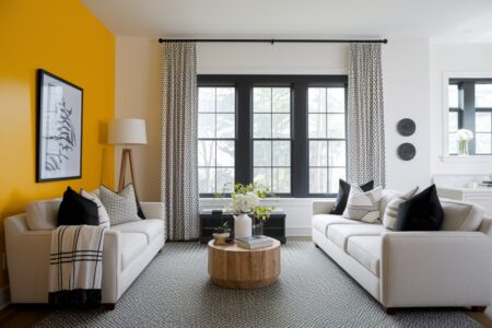 modern living room with yellow accent wall, light furniture, and black accents