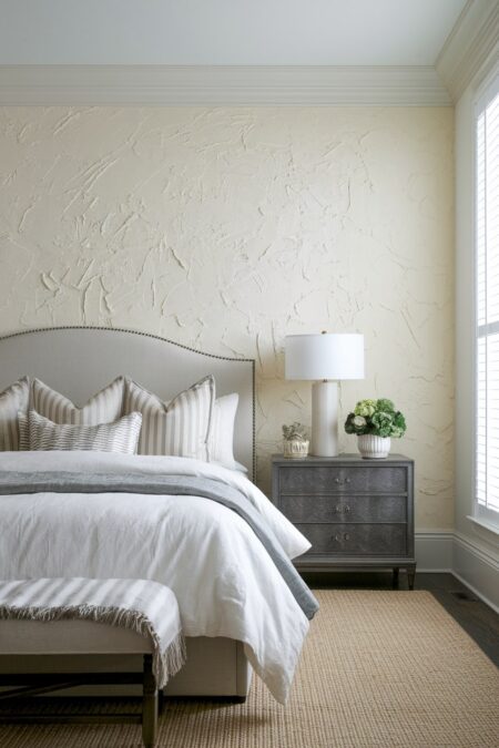 bedroom with textured cream walls and light gray headboard