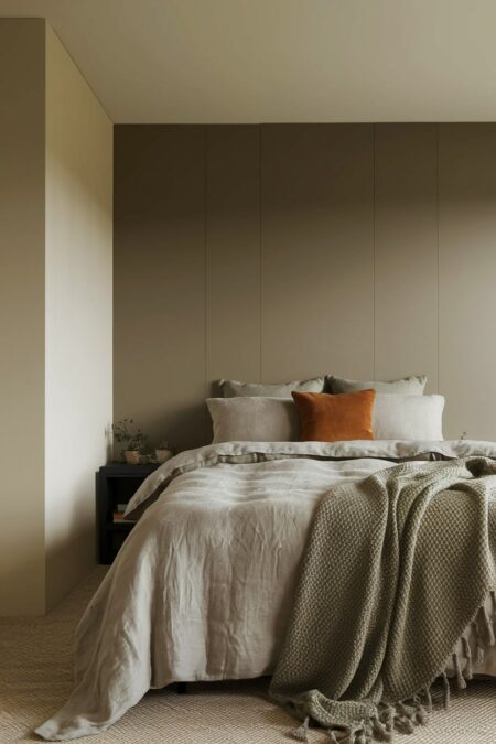 cozy neutral masculine bedroom in taupe, beige, and gray colors with terracotta accent pillow