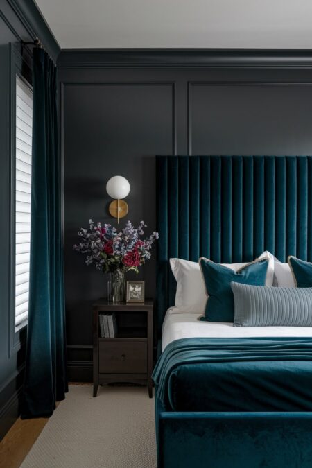 dark bedroom has charcoal gray walls, luxurious deep green velvet bed, headboard, and curtains