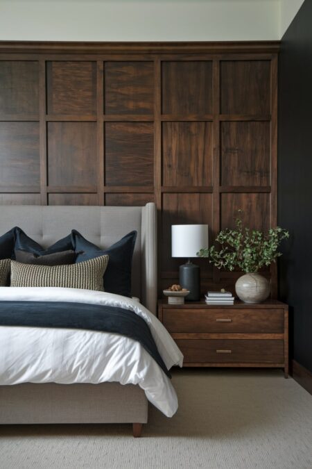 dark bedroom has dark wood panel wall with board and batten and wood nightstand