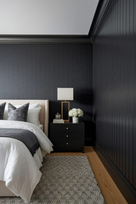 dark bedroom with black grasscloth wallpaper and wood wall paneling in black, light headboard
