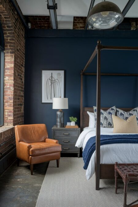 industrial loft style navy blue bedroom with exposed brick wall and leather chair