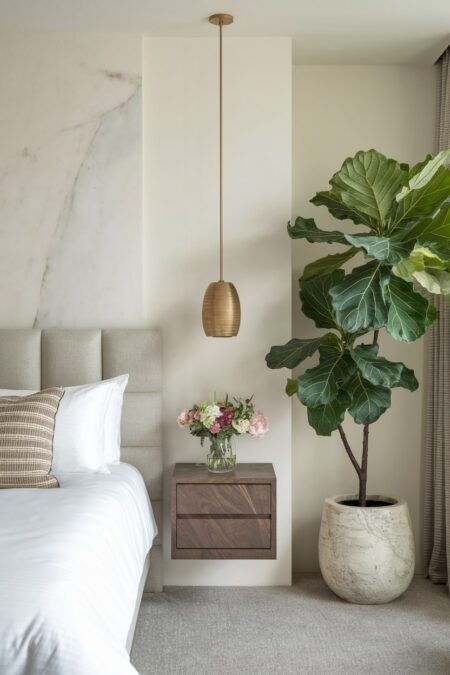 luxury bedroom with a Fiddle-leaf fig, floating nightstand, and marble tile behind the headboard