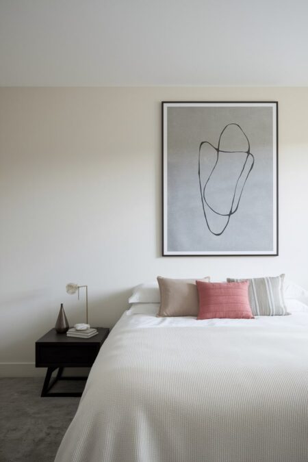 minimalist bedroom with a single abstract piece of art above the bed and pink accent pillow
