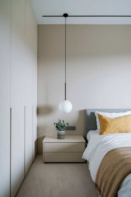 minimalist bedroom with fitted handleless wardrobe and yellow accent pillow