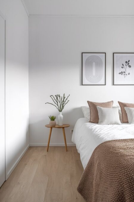 Scandinavian bedroom with a black line drawing and floral artwork, light brown accent pillows and throw blanket