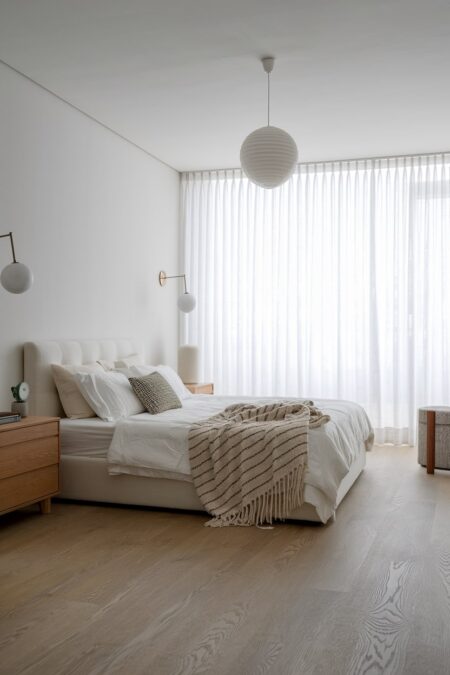 Scandinavian bedroom with clean lines, light furniture, spherical wall sconces, and sheer curtains