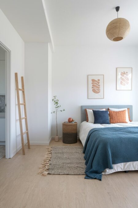 Scandinavian bedroom with muted blue accent pillow and throw blanket, muted terracotta pillows and artwork