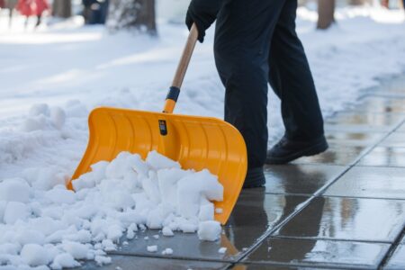 a person is clearing snow with a yellow snow shovel