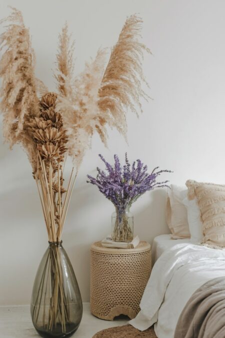 boho bedroom with a tall plume of pampas grass in a floor vase and dried lavender on the nightstand