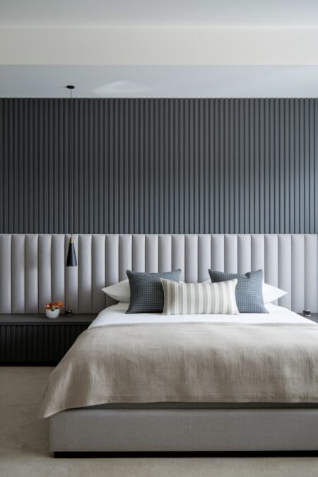 contemporary bedroom with light gray upholstered channel tufted wall-to-wall headboard and dark gray wall paneling