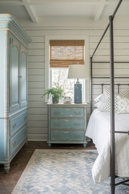 farmhouse bedroom with distressed nightstand and antique armoire