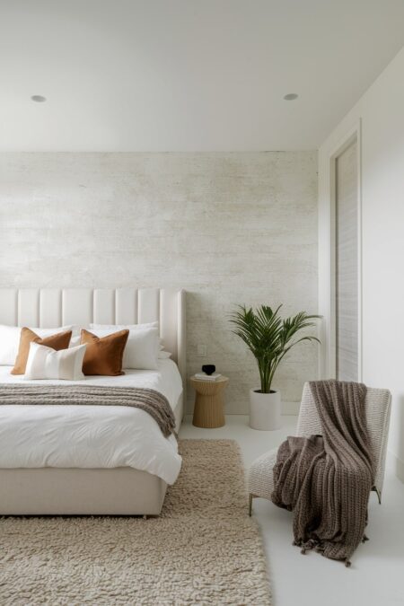 light contemporary bedroom with a neutral wallpaper, high pile area rug, and cream bed frame