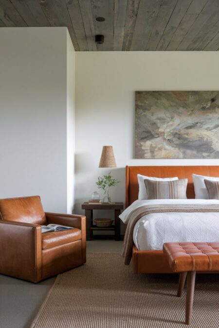 rustic bedroom with leather furniture, white walls, and wooden plank ceiling