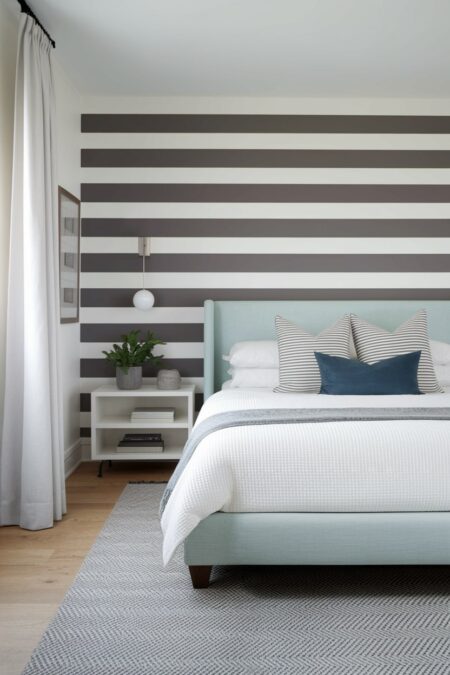 small bedroom has an accent wall with grayish brown and white horizontal stripes and light blue (with green undertones) upholstered bed frame