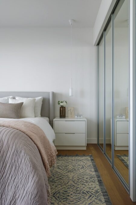 small bedroom with neutral uncluttered minimalist design and mirrored sliding wardrobe doors