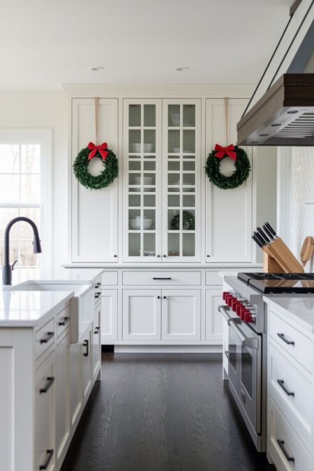 white kitchen with cabinets adorned with small Christmas wreaths
