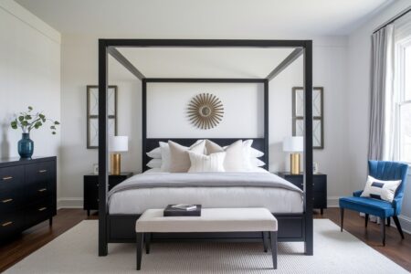 Art Deco bedroom with black furniture, four-posted bed, gold table lamps, and a blue velvet accent chair