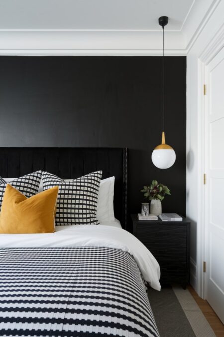 black and white bedroom with a black accent wall, black velvet headboard, and mustard yellow accent pillow