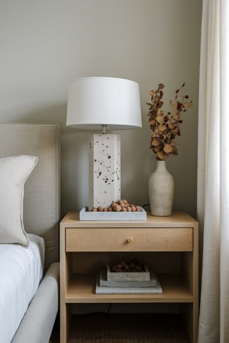 earthy bedroom with a travertine table lamp base and unglazed ceramic vase holding dried foliage