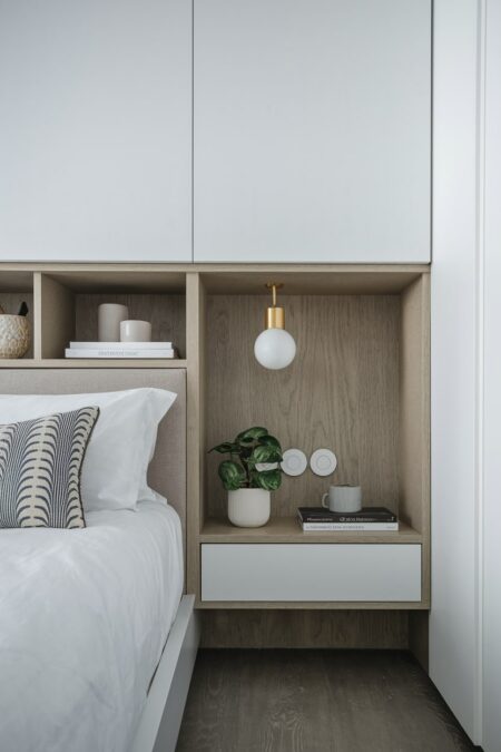 modern bedroom has a built-in headboard with storage and a white bedding