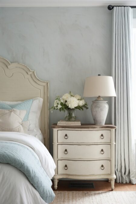 shabby chic bedroom with vintage bed frame and nightstand painted in cream color, distressed look