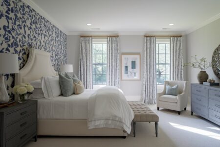 transitional bedroom has an accent wall with toile wallpaper, cream bed frame, white bedding, light gray walls, and a gray wood dresser