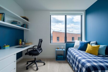 modern boy's bedroom with a blue accent wall, white desk, and wide blue gingham duvet cover